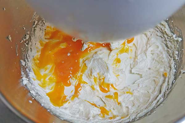 dodawanie żółtek do zmiksowanego masła