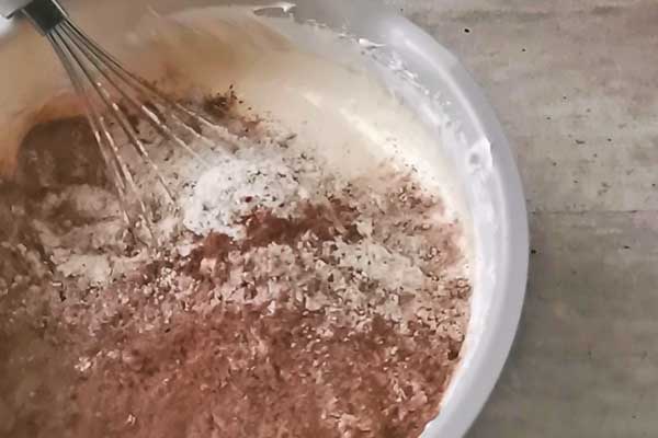dodawanie przesianej mąki z kakao do ciasta na biszkopt czekoladowy