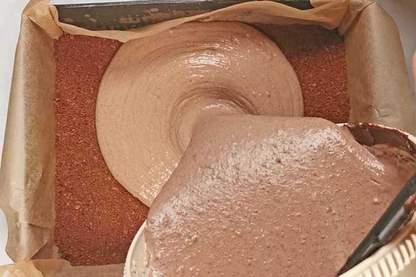 wylewanie czekoladowego sernika do formy do pieczenia