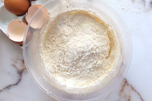 dodawanie przesianej mąki z migdałami do masy maślanej