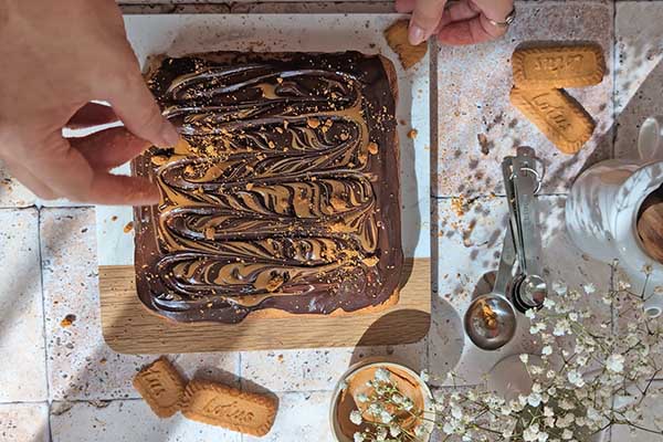 posypywanie ciasta biscoff pokruszonymi ciastkami lotus