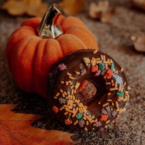 a donut with sprinkles next to a pumpkin