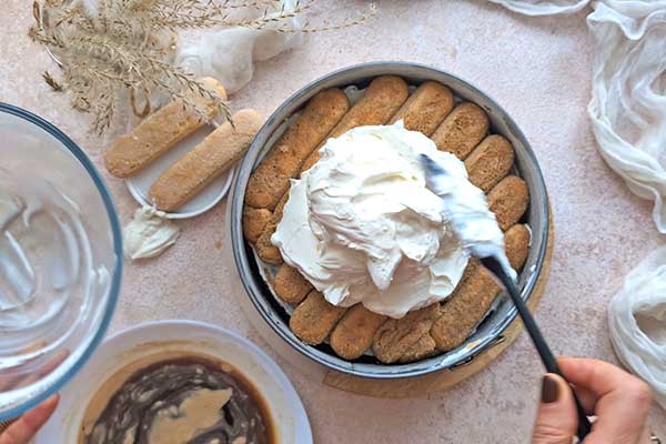 wykładanie kremu mascarpone na namoczone w kawie biszkopty do tiramisu