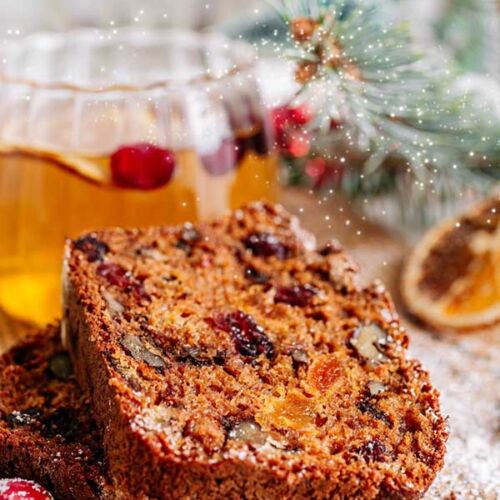a piece of fruit cake next to a glass of tea