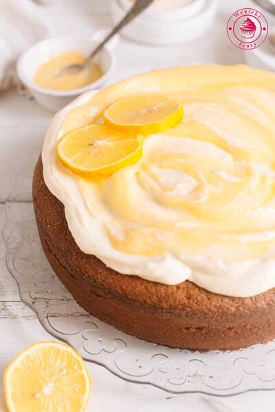 okrągłe ciasto pieczone w tortownicy podane z kremem mascarpone i lemon curd udekorowane plasterkami cytryny