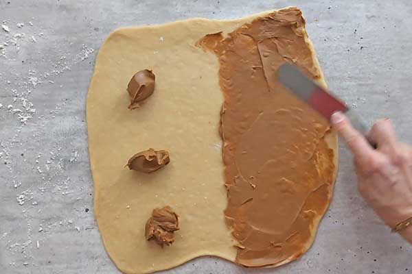 rozsmarowywanie kremu biscoff na rozwałkowanym cieście drożdżowym