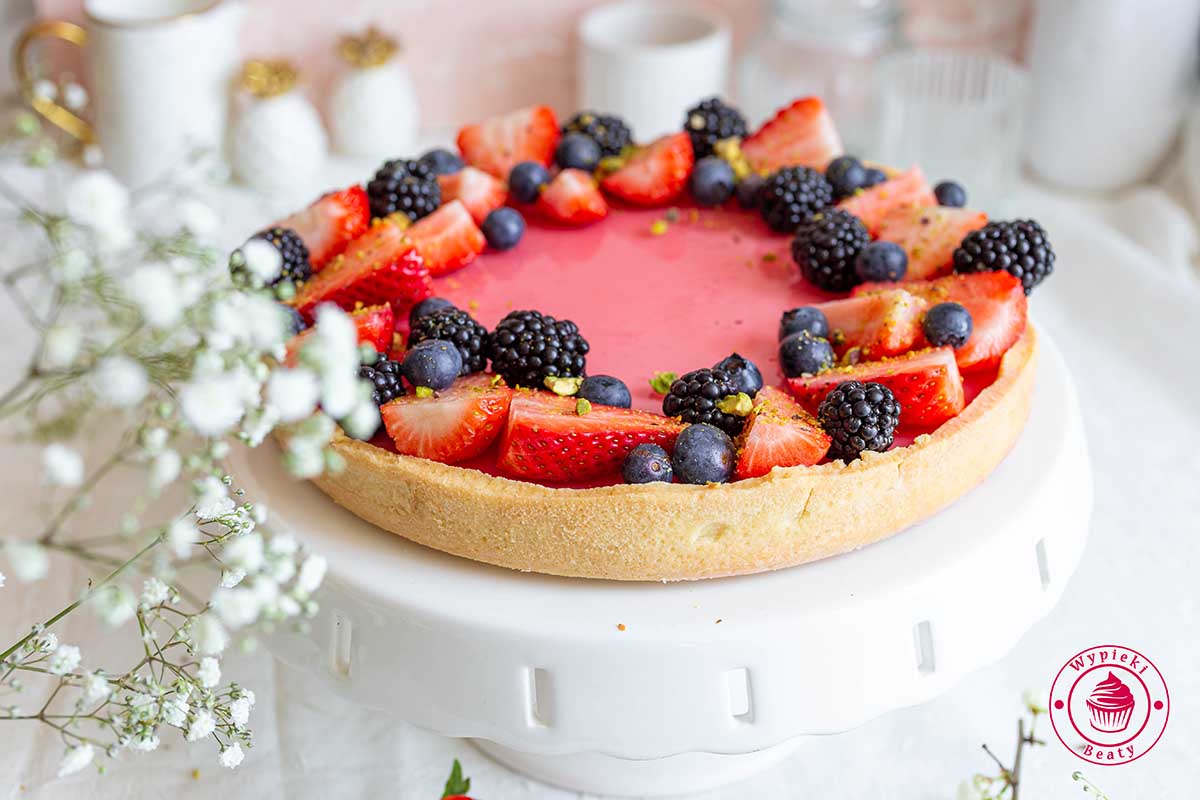 krucha tarta z owocami i galaretką umieszczona na białej paterze waniliowa tarta panna cotta z owocową galaretką i owocami