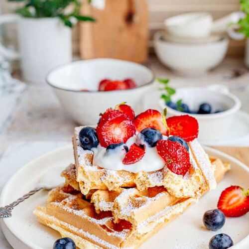 a plate of waffles with strawberries and blueberries