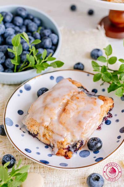 pojedyncze ciastko scones z lukrem leżące na deserowym talerzyku