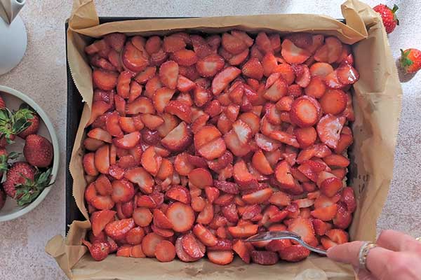 pokrojone truskawki wyłożone na podpieczony kruchy spód