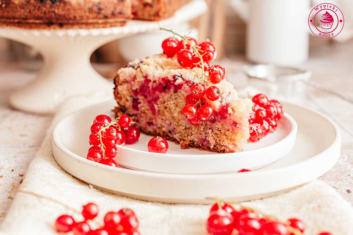 slice of red currant cake on a plate ucierane ciasto z porzeczkami i kruszonką ułożone na deserowym talerzyku