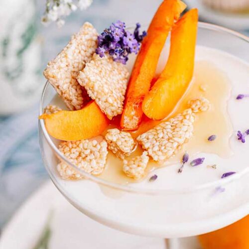 zbliżenie na panna cottę w ozdobnym pucharku z kawałkami moreli i pokruszonymi sezamkami