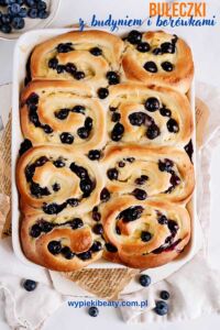 Chocolate bundt cake with blueberries Top view of a baking tin filled with baked yeast swirl buns with custard and blueberries.
