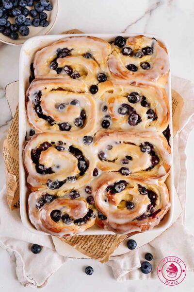 flat lay photo of sweet rolls with blueberies and icing