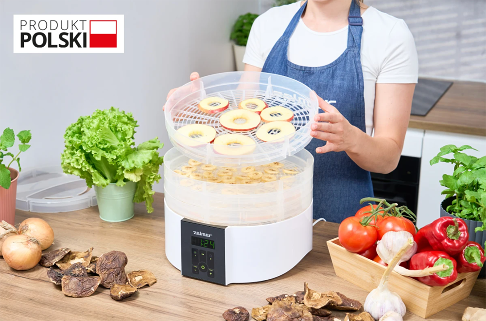 suszarka a w tle kobieta układająca na niej suszone owoce