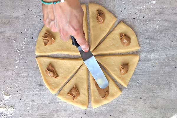 nakładanie kremu biscoff na trójkąty z ciasta drożdżowego