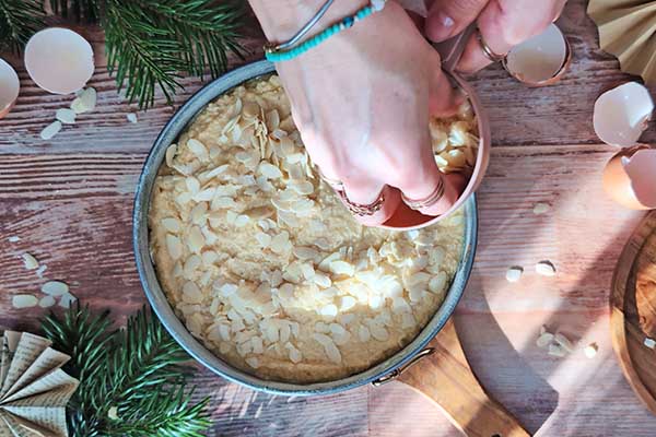 posypywanie wierzchu ciasta płatkami migdałowymi przed jego pieczeniem