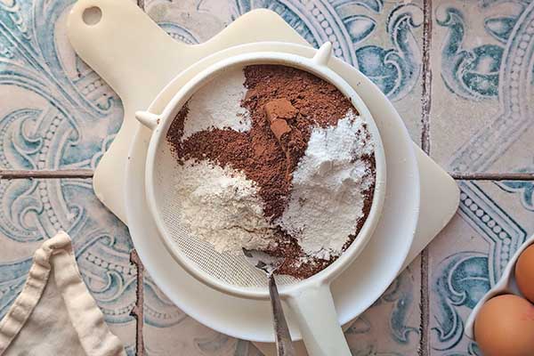 Ciasto kakaowo-jogurtowe przesiewanie mąki z gorzkim kakao