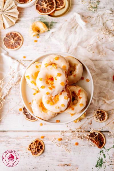 wilgotne i miękkie pieczone pączki pomarańczowe z lukrem i skórką pomarańczową domowe pieczone oponki z pomarańczą i pomarańczowym lukrem