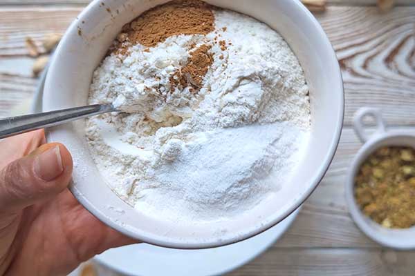 Ciasto marchewkowe z pistacjami mieszanie mąki z proszkiem do pieczenia i cynamonem