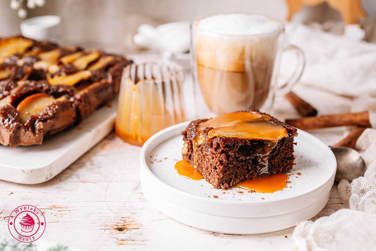 widok na ukrojony kawałek ciasta piernikowego z plastrami jabłka na wierzchu oblany sosem karmelowym wilgotne i proste odwrócone ciasto piernikowe pieczone z karmelizowanymi jabłkami