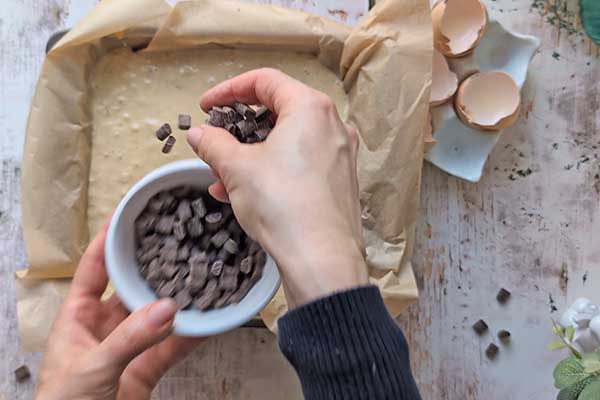 Protein Banana Cake posypywanie ciasta bananowego kawałkami czekolady