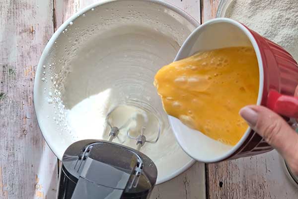 Puszyste i wilgotne ciasto na kremówce dodawanie roztrzepanych jajek do masy na ciasto