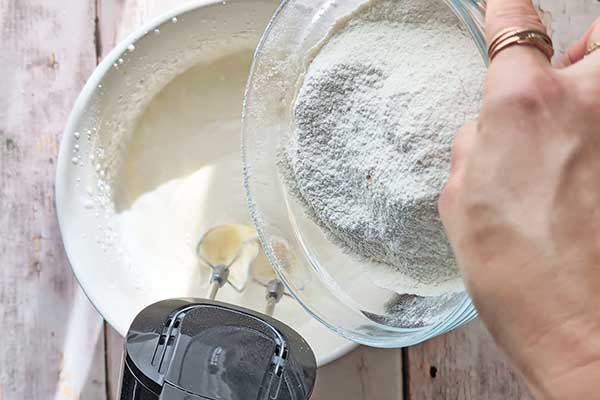 Puszyste i wilgotne ciasto na kremówce dodawanie porcjami przesianej mąki z proszkiem do pieczenia