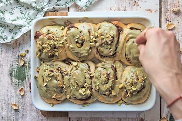 posypywanie pistacjowych drożdżówek posiekanymi pistacjami