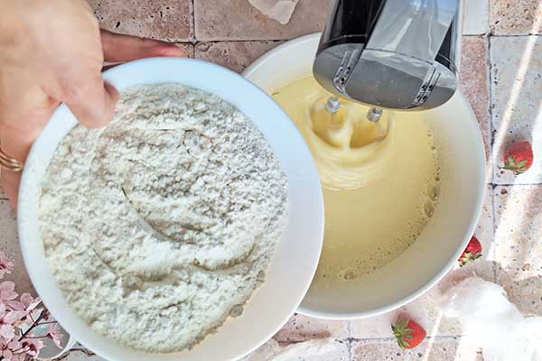 dodawanie mąki z proszkiem do pieczenia do ciasta z truskawkami