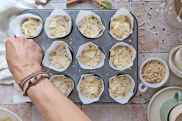 Migdałowe muffiny z rabarbarem posypywanie muffinek kruszonką oraz siekanymi migdałami