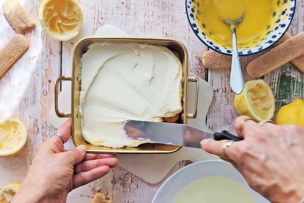 Limoncello tiramisu wykładanie części kremu cytrynowego na biszkopty w formie