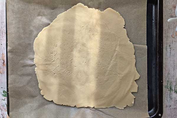 Tarta galette z borówkami rozwałkowane kruche ciasto do galette ułożone na dużej blaszce z piekarnika