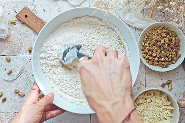 Ciastka z pistacjami i białą czekoladą mieszanie ciasta z mąką