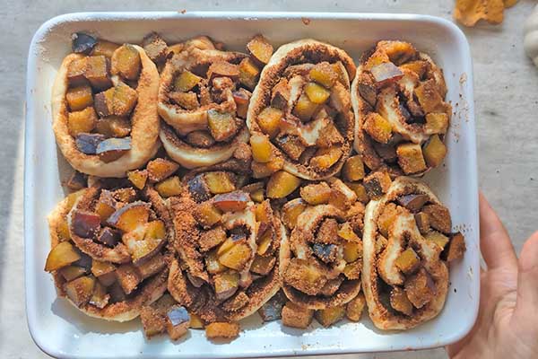 Jesienne cynamonki ze śliwkami cynamonki ze śliwkami ułożone w formie do pieczenia
