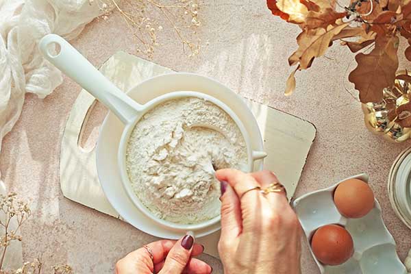 Marmurkowe ciasto cynamonowe przesiewanie mąki przez sitko